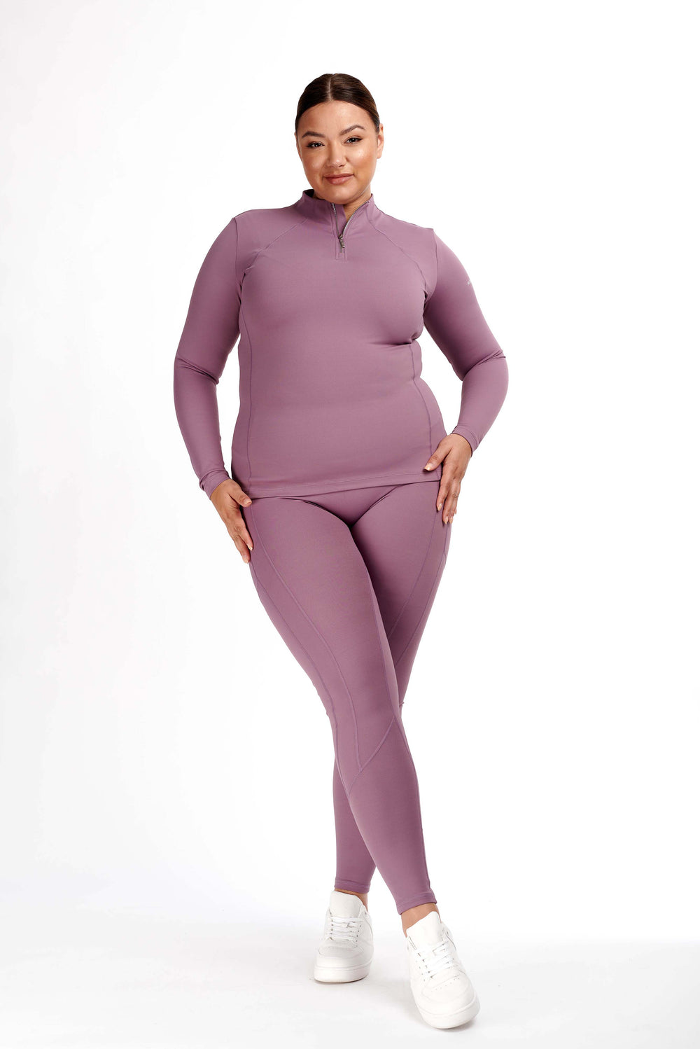 Woman in purple horse riding tights and matching long-sleeve top.