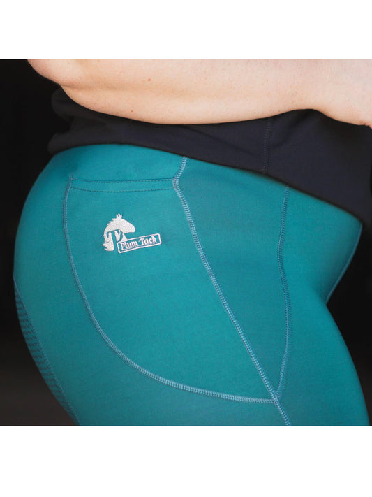 Person wearing teal horse riding tights with a white logo.