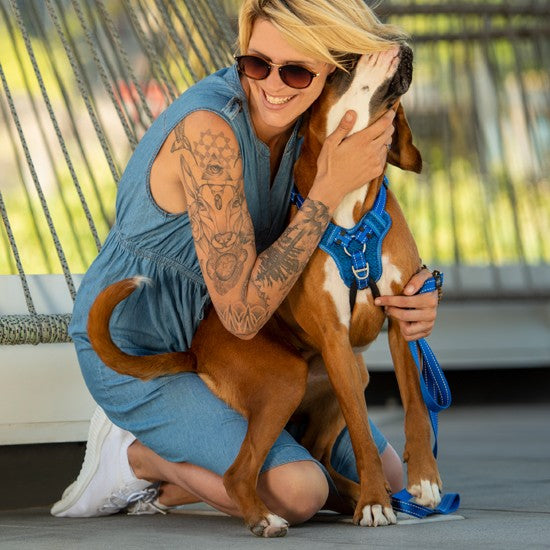 Woman hugging dog with blue Rogz harness and leash.