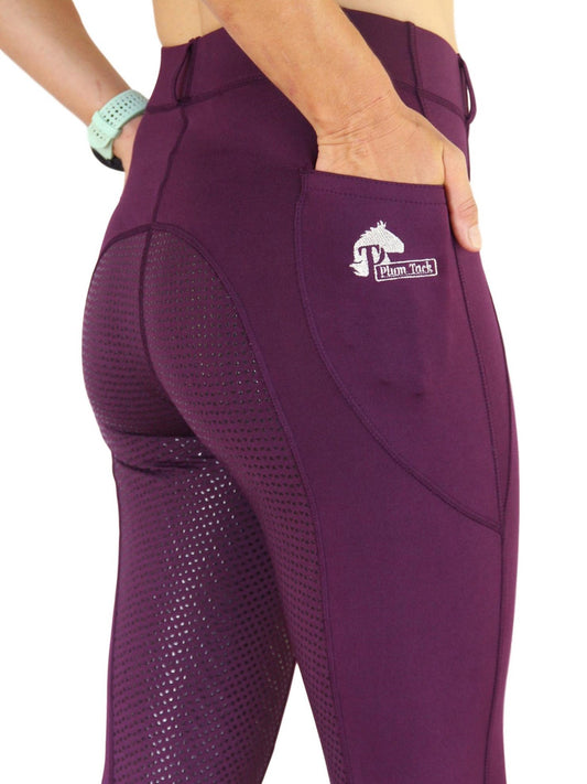 Woman wearing purple horse riding tights with ventilated thigh panels.