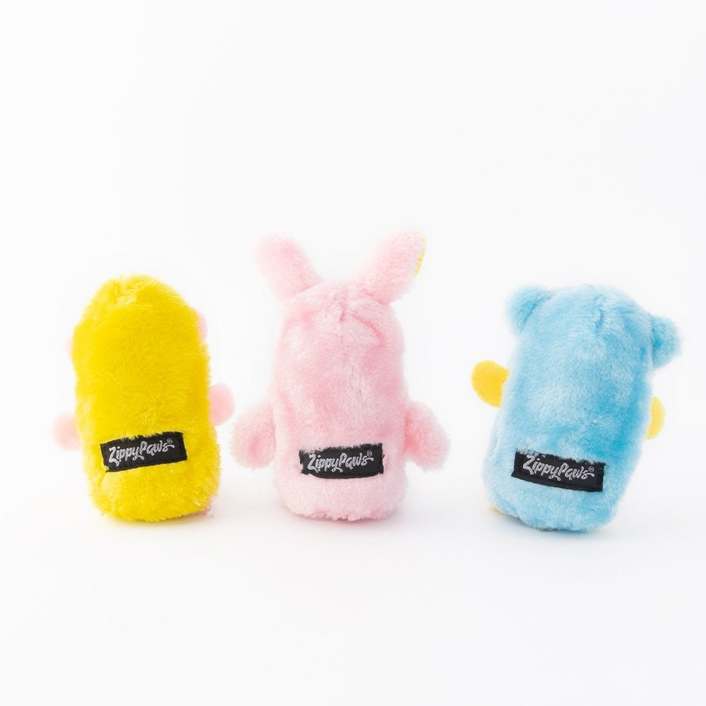 Zippy Paws plush dog toys in yellow, pink, and blue colors.