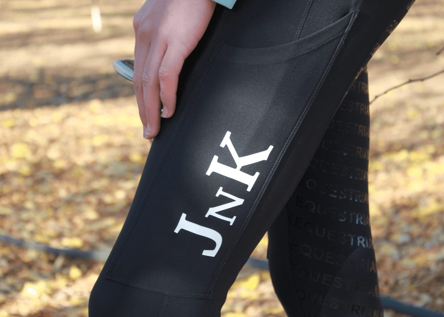 Close-up of black horse riding tights with white logo on thigh.