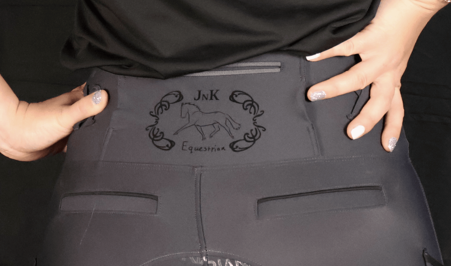 Close-up of hands adjusting black horse riding tights with logo.